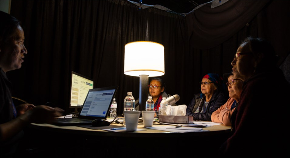 Multiple people speaking into a microphone for language preservation project